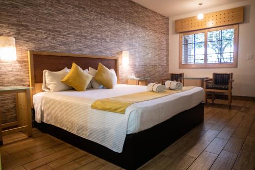 ein Schlafzimmer mit einem großen Bett und einer Ziegelwand in der Unterkunft Hotel Colonial Mexicali in Mexicali