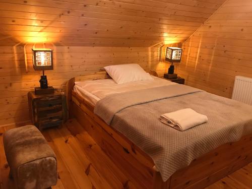 Una cama en una habitación de madera con dos lámparas. en Przystanek Beskidy, en Brenna