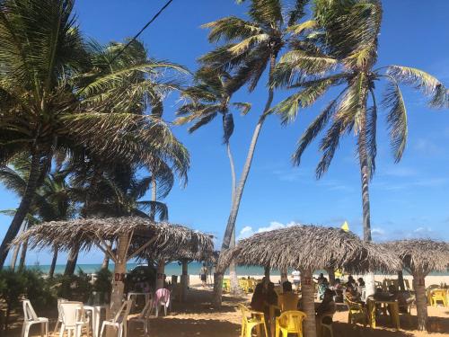 a beach with palm trees and chairs and the ocean at Chalés Polinésia in Touros