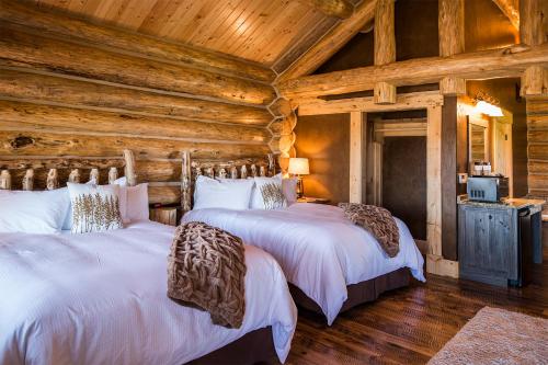 two beds in a log cabin bedroom with wooden ceilings at Kodiak Mountain Resort in Afton