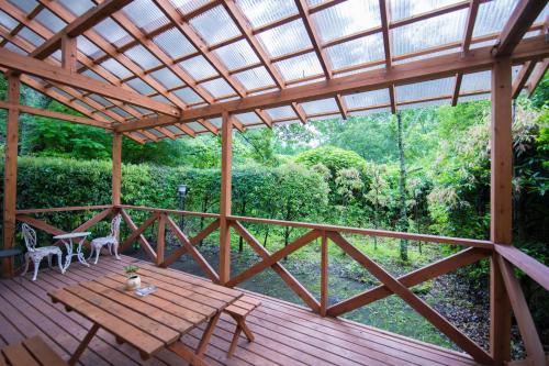 a wooden deck with a table and chairs on it at Yufuin Tsukahara Kogen Sanso Donguri in Yufuin