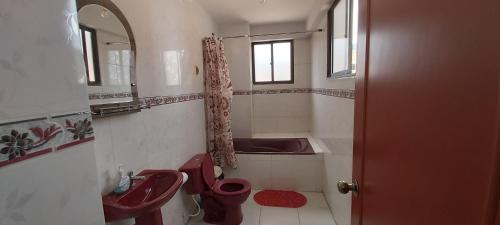 uma casa de banho com um WC vermelho e um lavatório. em Garzonier Centrico em Cochabamba