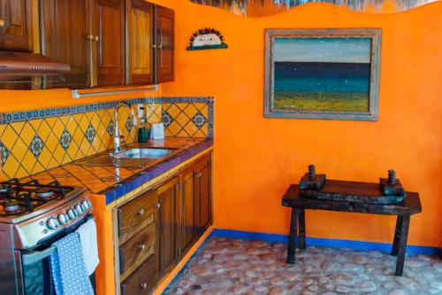 a kitchen with a sink, stove, and cabinets at Aurinko Bungalows in Sayulita