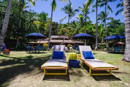 two lounge chairs and umbrellas in a yard at Maion Hotel e Boutique in Praia do Espelho