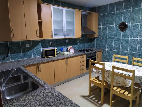 a kitchen with a sink and a table with chairs at Casa Cabral : Big Apartment next to the beach in Tarrafal