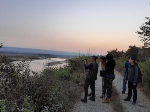 a group of people taking pictures of a river at Hotel Tiger Tops Sauraha in Sauraha