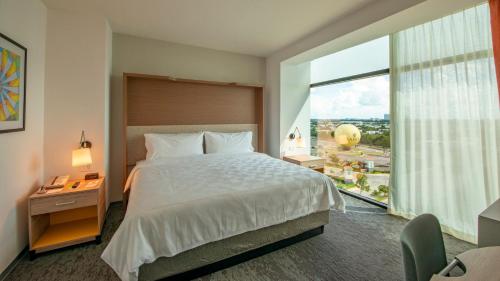 a bedroom with a large bed and a large window at Holiday Inn & Suites - Merida La Isla by IHG in Mérida