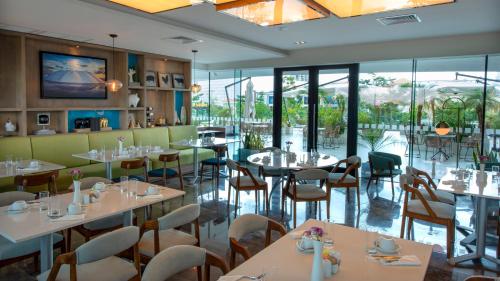 a restaurant with white tables and chairs and windows at Holiday Inn & Suites - Merida La Isla by IHG in Mérida