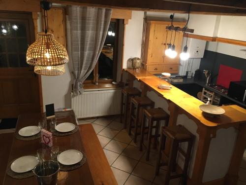 uma cozinha com um bar com mesas e bancos de madeira em La Pénates em Château-Regnault-Bogny