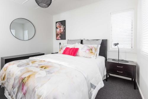 - une chambre blanche avec un grand lit fleuri dans l'établissement Awesome Beach House on Oceanview Road, à Mount Maunganui