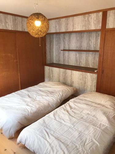 a bedroom with two beds and a chandelier at 蒼 aoi in Shingū