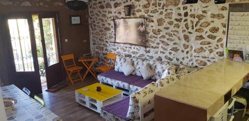 a living room with a couch and a stone wall at Maison la branche d oiseaux in Boulaouane