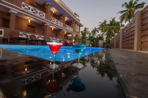 two martini glasses sitting on top of a swimming pool at Traveller Lodge Ngapali by River Top in Ngapali