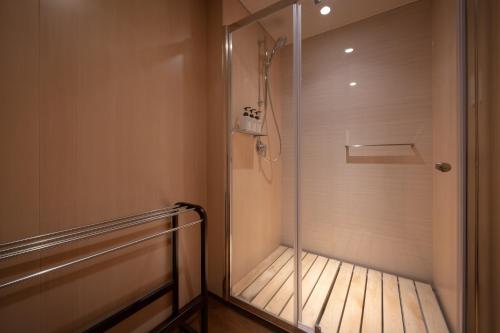a walk in shower with a glass door in a bathroom at Oushuku Onsen Choeikan in Shizukuishi