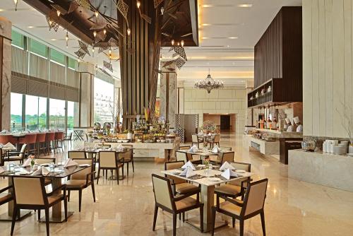 a dining room with tables and chairs in a restaurant at Gift City Club, a member of Radisson Individuals in Gandhinagar