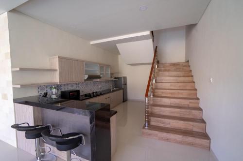 a room with a staircase and a kitchen with stools at Juada Garden in Seminyak