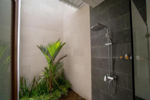 a shower with a shower head in a bathroom with plants at Juada Garden in Seminyak
