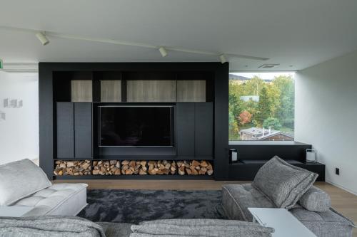 a living room with a large tv and a fireplace at Yama no Oto in Furano