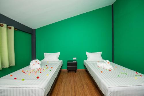 two beds in a room with green walls at Traveller Lodge Ngapali by River Top in Ngapali