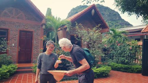 a man and a woman standing outside of a house at Trang An Village Homestay in Ninh Binh