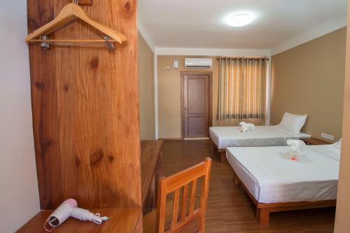 a room with two beds and a wooden wall at Traveller Lodge Ngapali by River Top in Ngapali