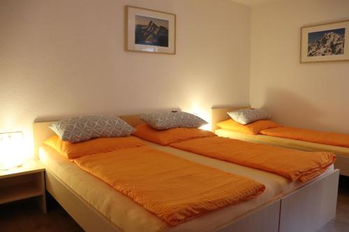 two beds in a room with orange sheets at Haus Aperies in Pettneu am Arlberg