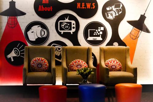 a waiting room with three chairs and a wall with stickers at News Hotel Waru Sidoarjo in Waru
