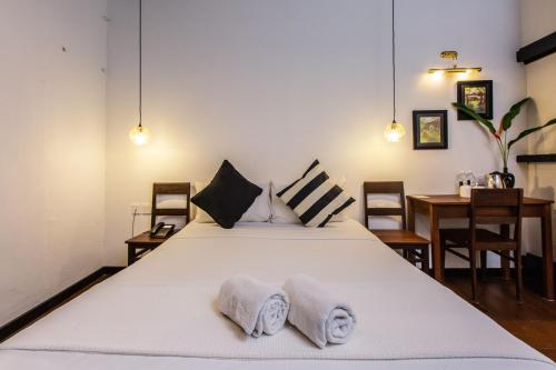 a bedroom with a large white bed with two towels at The Marian Boutique Lodging House in Kuching