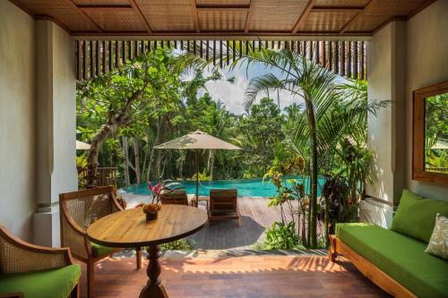 a living room with a table and a pool at Adiwana Unagi Suites in Ubud