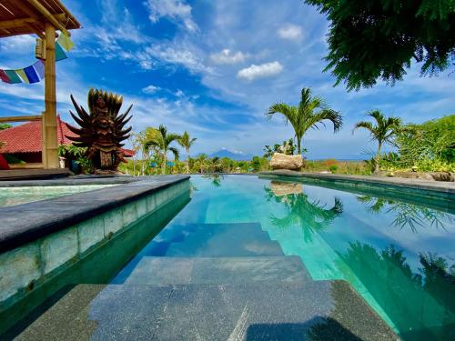 a swimming pool at a resort with palm trees at Odiyana Bali Retreat in Banyuwedang