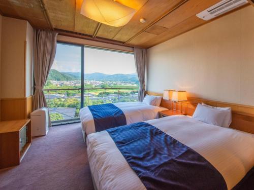 una camera d'albergo con due letti e una grande finestra di Yamashiro Onsen Miyabi no Yado Kaga Hyakumangoku a Kaga
