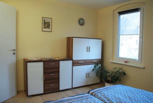ein Schlafzimmer mit einem Schrank, einer Kommode und einem Fenster in der Unterkunft Ferienwohnung mit Balkon in Schmölln in Schmölln