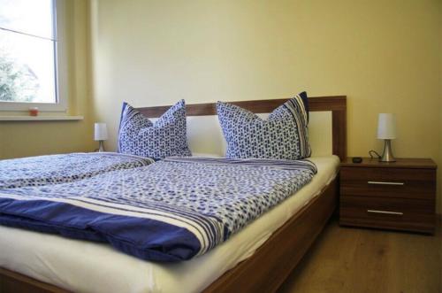 Schlafzimmer mit einem Bett mit blauen und weißen Kissen in der Unterkunft Ferienwohnung mit Balkon in Schmölln in Schmölln