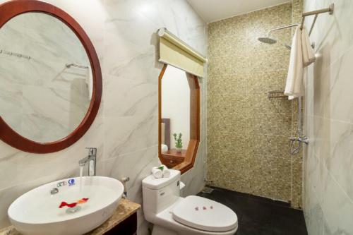 W łazience znajduje się umywalka, toaleta i lustro. w obiekcie Flame Flowers Homestay w Hoi An