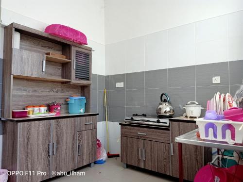 cocina con armarios de madera y fogones en Ilham Imani Homestay en Kampung Gurun