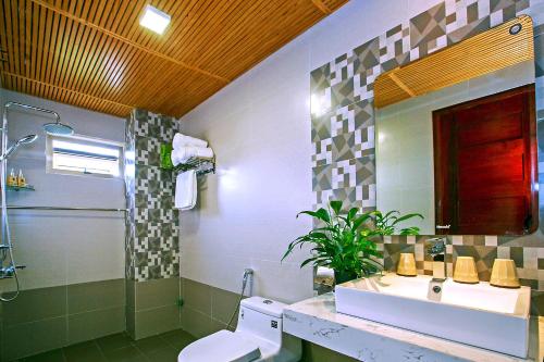 uma casa de banho com um lavatório, um WC e um chuveiro em Silk and Sea Hotel em Hoi An