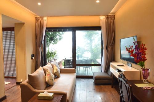 a living room with a couch and a large window at Brightland Resort & Spa in Mahabaleshwar