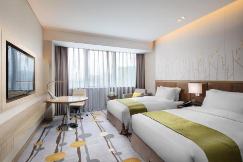 a hotel room with two beds and a desk at Holiday Inn Shaoguan Downtown by IHG in Shaoguan
