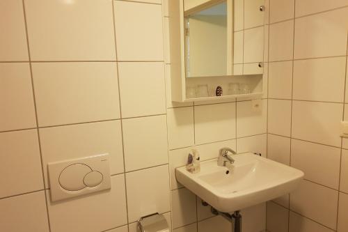 ein weißes Badezimmer mit einem Waschbecken und einem Spiegel in der Unterkunft Ferienwohnung Resort Walensee 98 - Seehöckli in Quarten