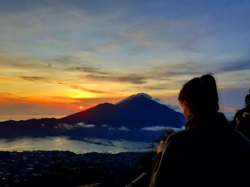 a woman standing on top of a mountain watching the sunset at Batur Volcano Guesthouse in Kintamani