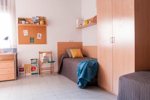 ein kleines Schlafzimmer mit einem Bett und einem Schrank in der Unterkunft Residencia Tomás Alfaro Fournier in Vitoria-Gasteiz