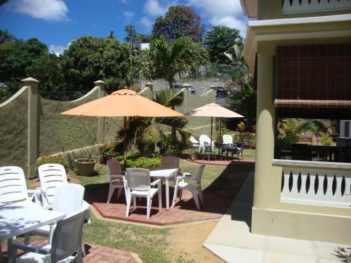 a patio with white chairs and tables and umbrellas at Bel Air Hotel in Victoria