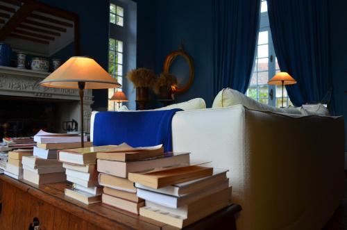 a pile of books sitting on a table next to a couch at Saint Victor La Grand' Maison in Ingrandes
