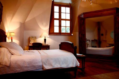 a bedroom with a bed and a bathroom with a tub at Saint Victor La Grand' Maison in Ingrandes