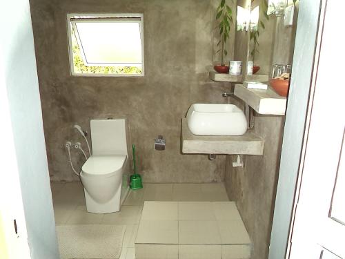 a bathroom with a toilet and a sink and a window at The Rock House in Katunayake