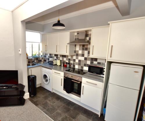 a kitchen with white cabinets and a dishwasher at Perfect location for Racecourse and town centre in Cheltenham