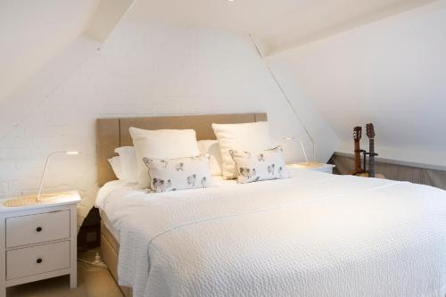 a bedroom with a white bed with white sheets and pillows at Jasmine Cottage in Charlbury