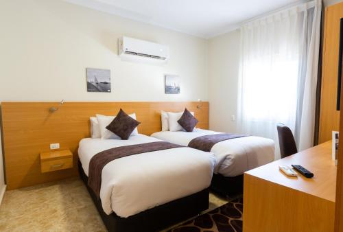 a hotel room with two beds and a desk at Mercure Ismailia Forsan Island in Ismailia