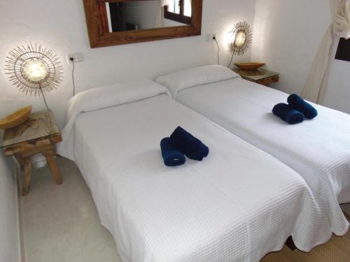 Dos camas en una habitación con almohadas azules. en Casa Sol & Mar, en Sant Josep de sa Talaia