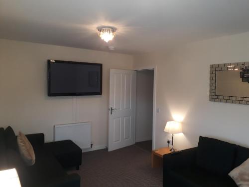 a living room with a flat screen tv on the wall at Crystal Apartments in Airdrie